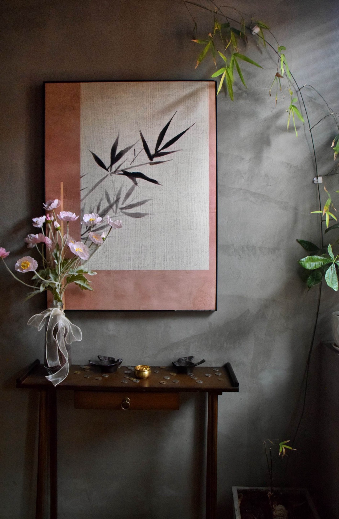 A console with pink poppies, old coins, and a bamboo ink painting