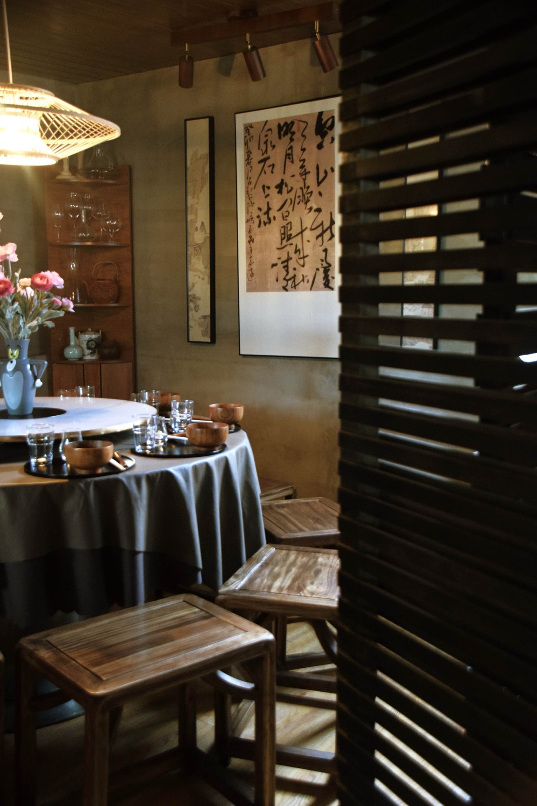 The private dining room — round table, linen, wooden bowls, calligraphy